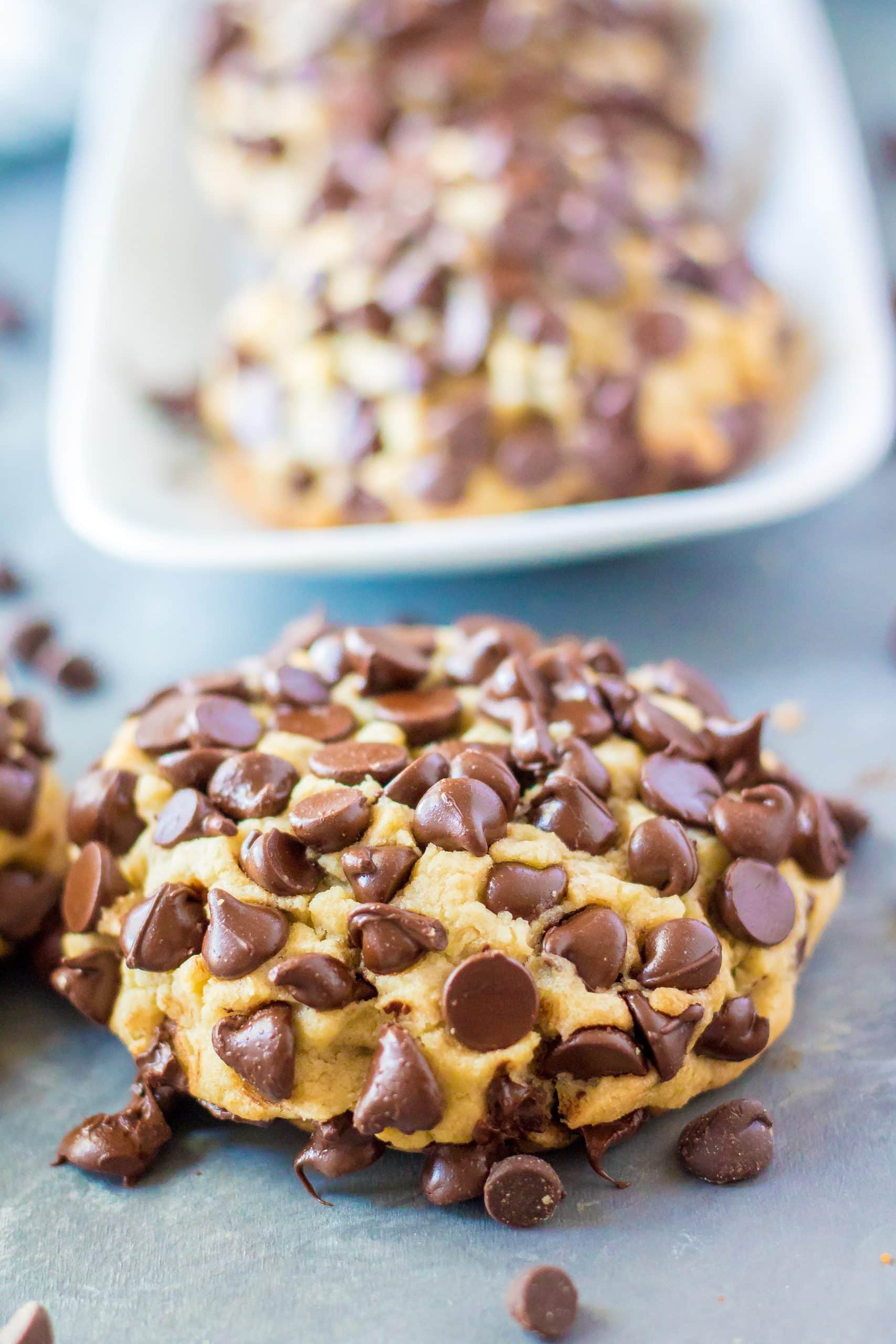 Giant Chocolate Chip Cookies (Disney Copycat) giant chocolate chip cookie in front of a white platter of cookies