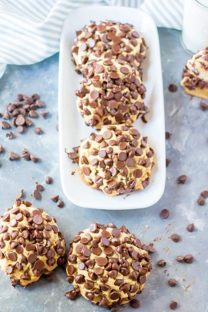 giant chocolate chip cookie in front of a white platter of cookies