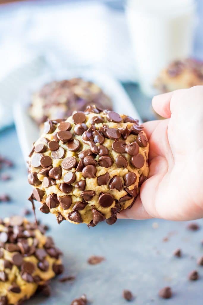 a hand holding a giant chocolate chip cookie