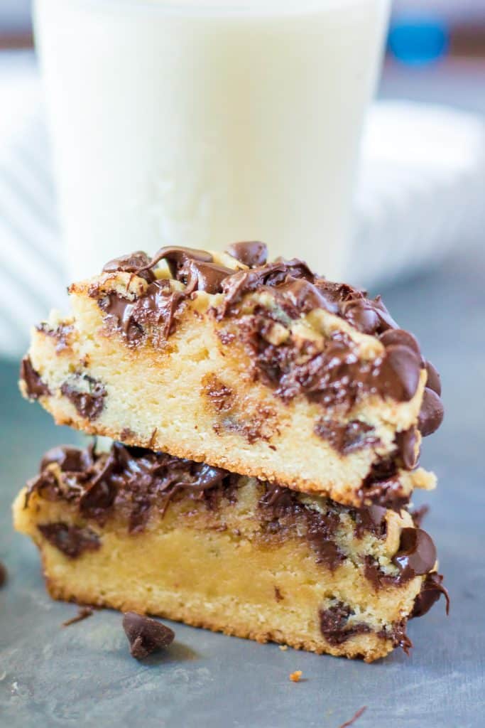 a Disney copycat giant chocolate chip cookie cut in half an stacked together in front of a glass of milk