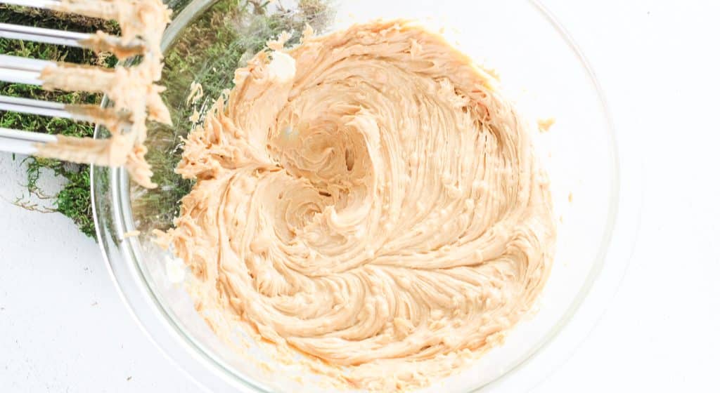 creamy powdered sugar peanut butter mixture whipped in a glass mixing bowl