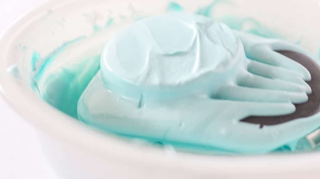 peanut butter egg dipped in baby blue chocolate resting on the tines of a fork