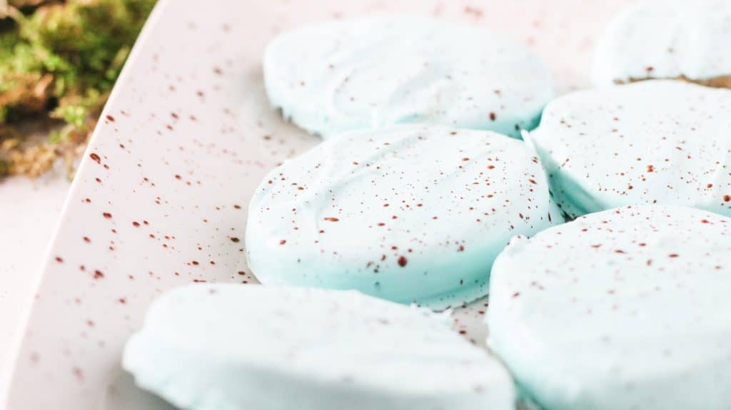 powder blue chocolate covered peanut butter eggs flecked with cocoa powder on a white plate
