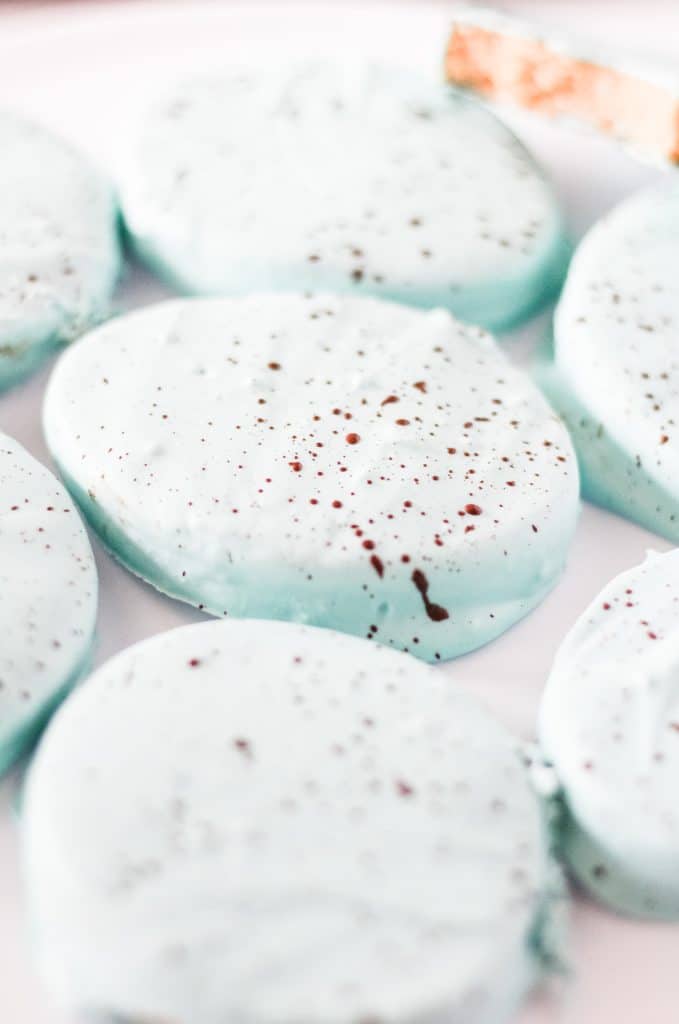 powder blue chocolate covered peanut butter eggs flecked with cocoa powder on a white plate