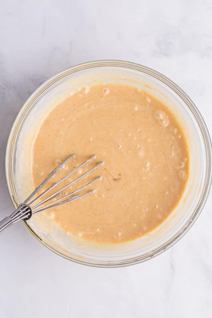 sheet pan peanut butter pancake batter being whisked in a glass mixing bowl