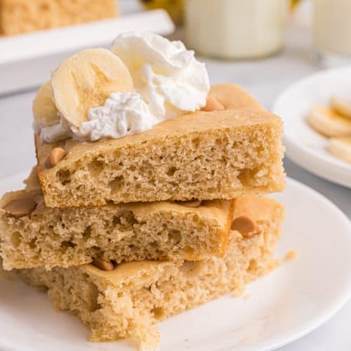 square slices of sheet pan peanut butter pancakes stacked on a white plate