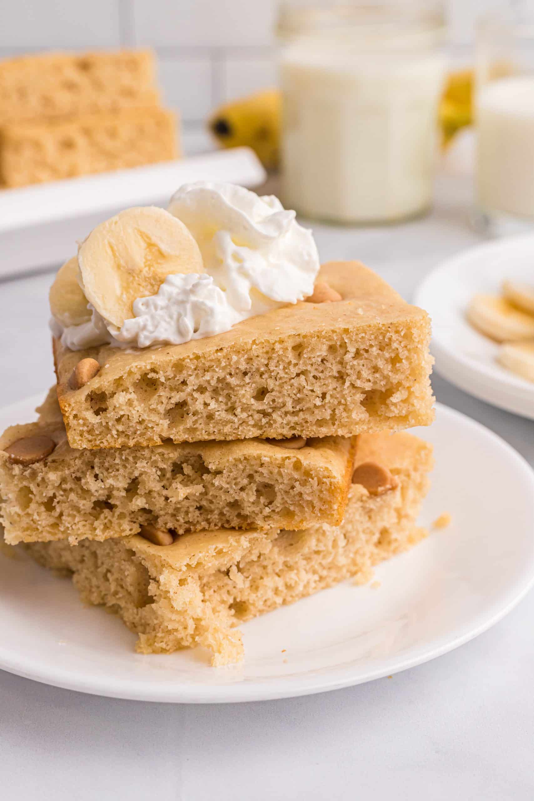 square slices of sheet pan peanut butter pancakes stacked on a white plate