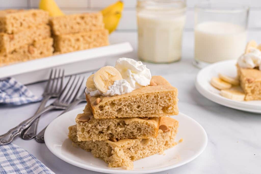 square slices of sheet pan peanut butter pancakes stacked on a white plate