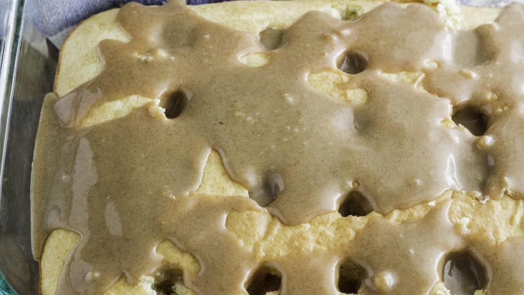 buttery cinnamon sauce poured over a cake with holes poked in it