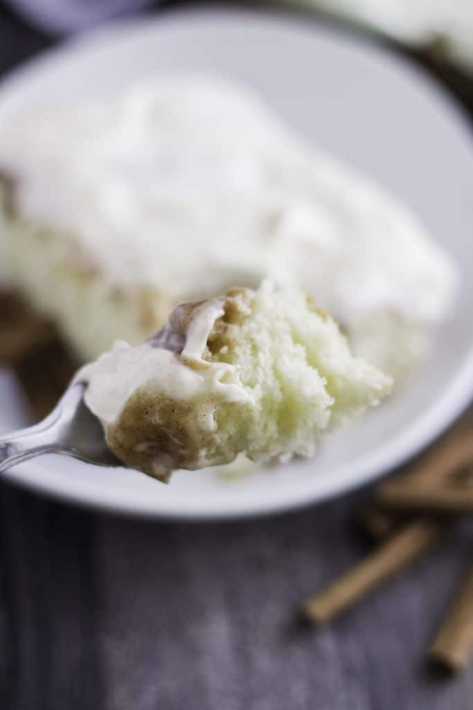 a silver fork holding up a bite of cinnamon roll poke cake