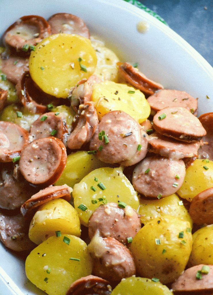 Instant pot creamy kielbasa and potatoes in a white serving platter with a bowl of shredded Parmesan cheese on the side