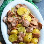 Instant pot creamy kielbasa and potatoes in a white serving platter with a bowl of shredded Parmesan cheese on the side