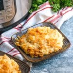 Instant pot funeral potatoes on small brown plates sitting in front of a pressure cooker