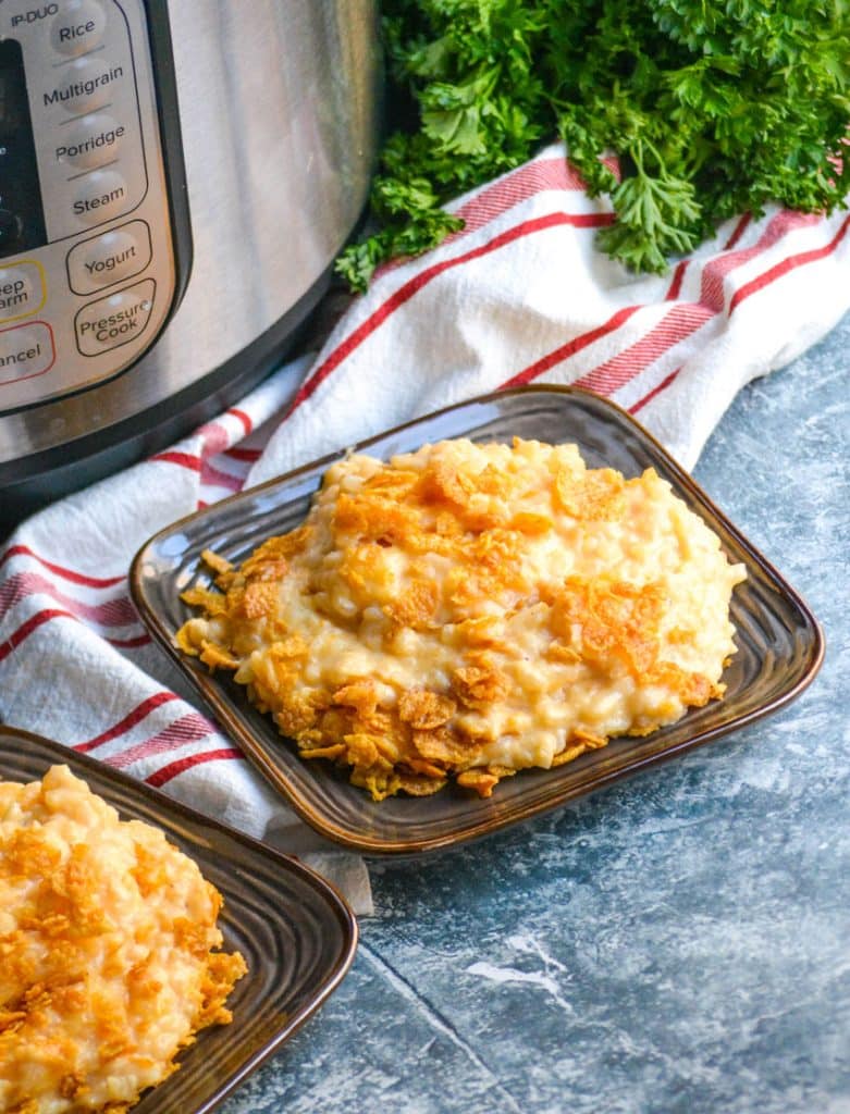 Instant pot funeral potatoes on small brown plates sitting in front of a pressure cooker