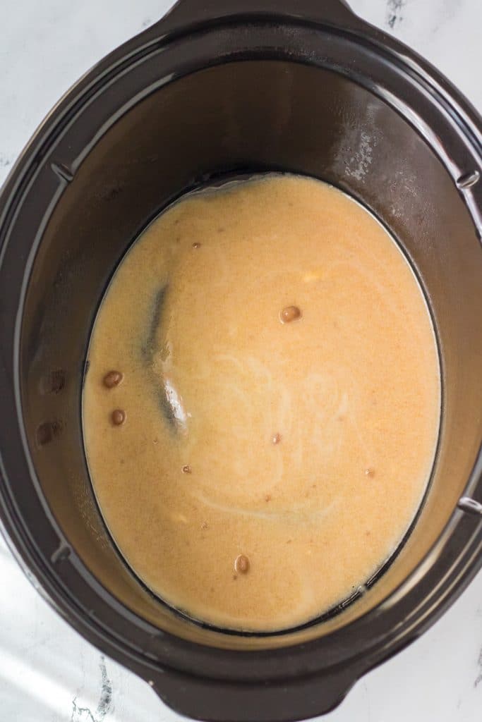 brown sugar & butter sauce in the bottom of a black crock pot for the base of slow cooker sticky buns