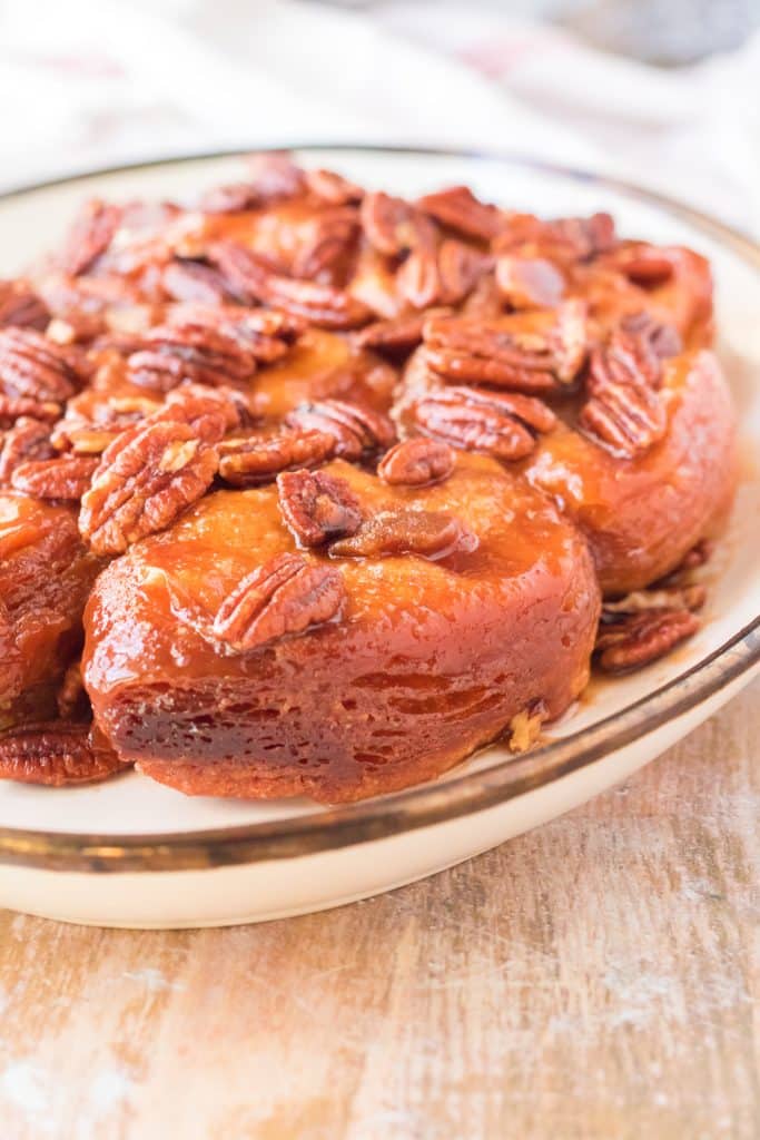 slow cooker sticky buns topped with pecans on a white oval serving platter