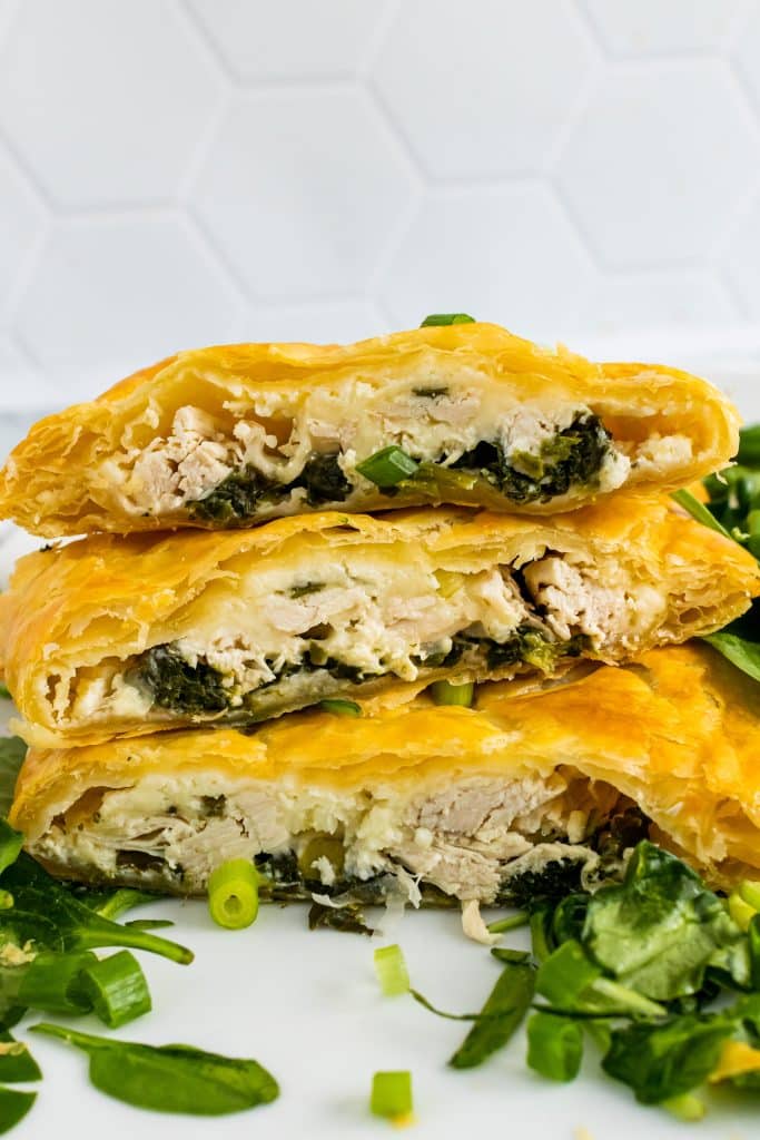 three slices of greek chicken and spinach pie stacked on top of each other
