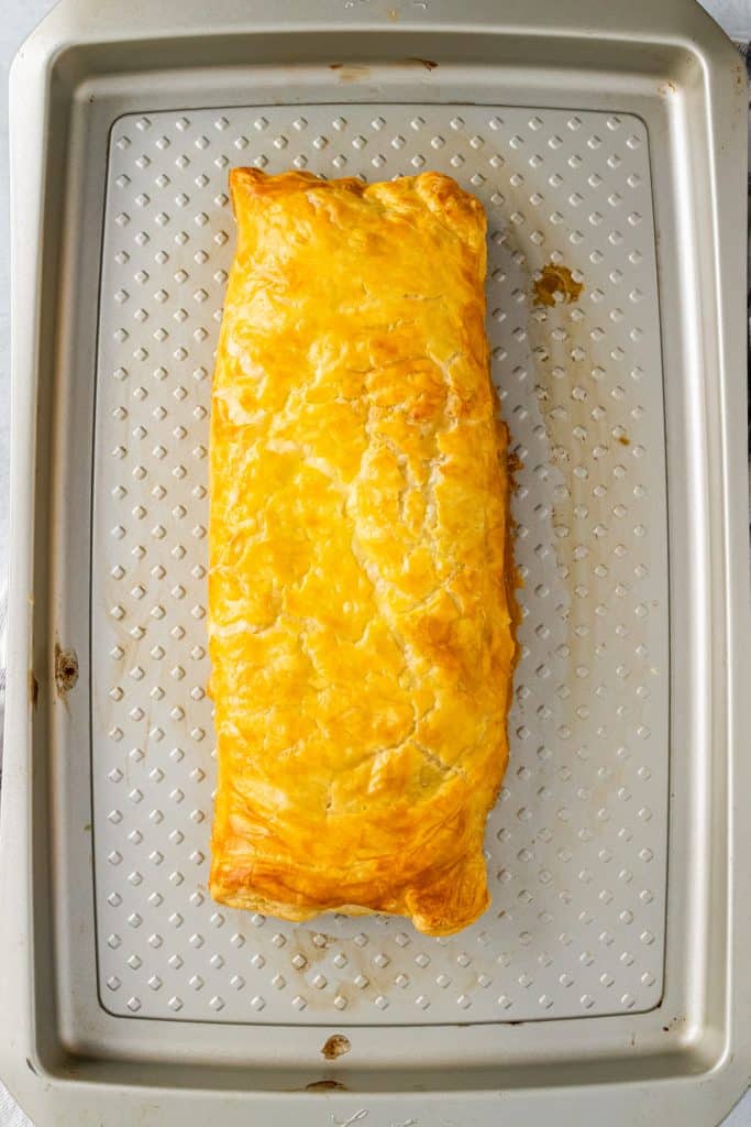 golden brown baked greek chicken and spinach pie on a metal baking sheet