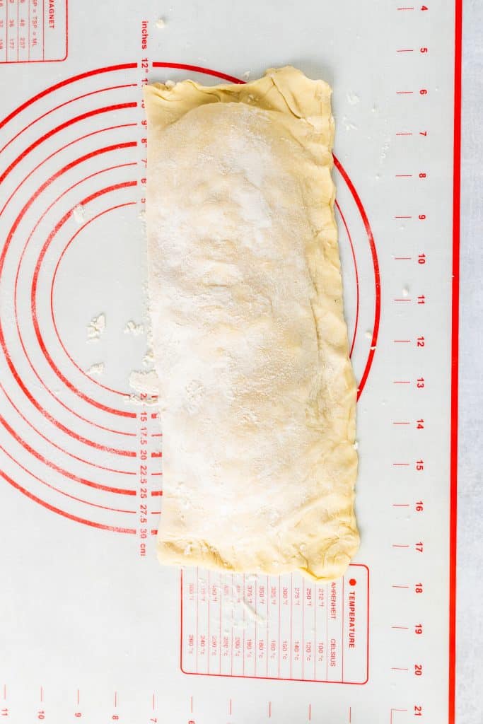 chicken and spinach stuffed puff pastry folded up and edges sealed on a plastic cutting mat