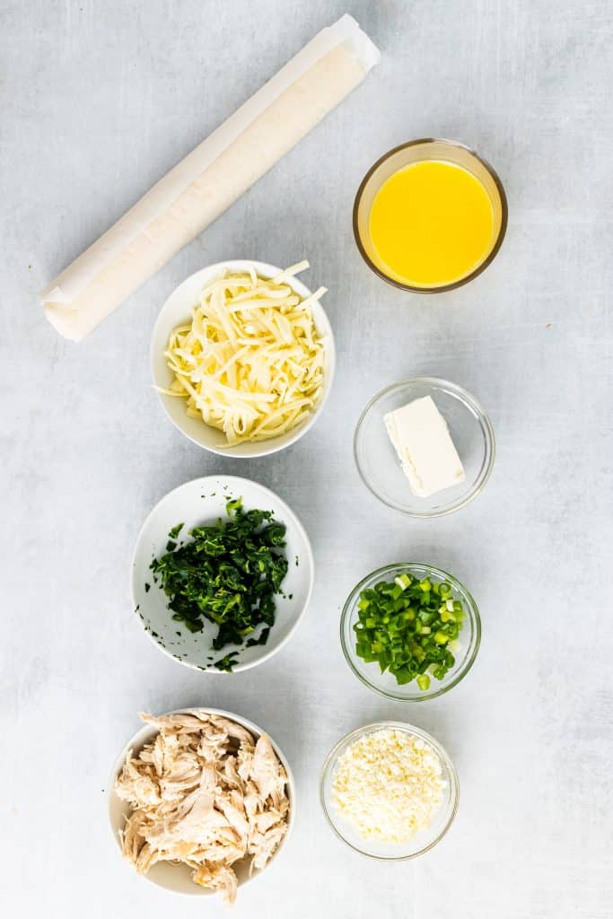 overhead image showing all of the measured ingredients needed to make a greek chicken and spinach pie with puff pastry