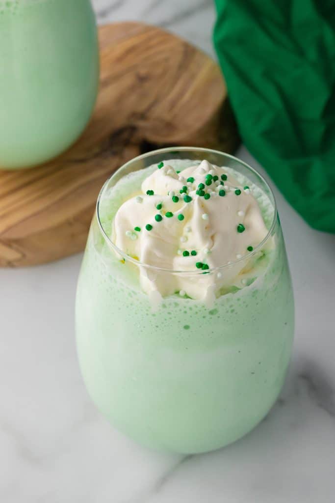 copycat shamrock shake in a glass cup topped with whipped cream and green sprinkles
