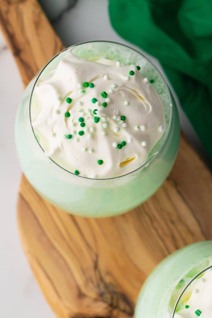 copycat shamrock shake in a glass cup topped with whipped cream and green sprinkles