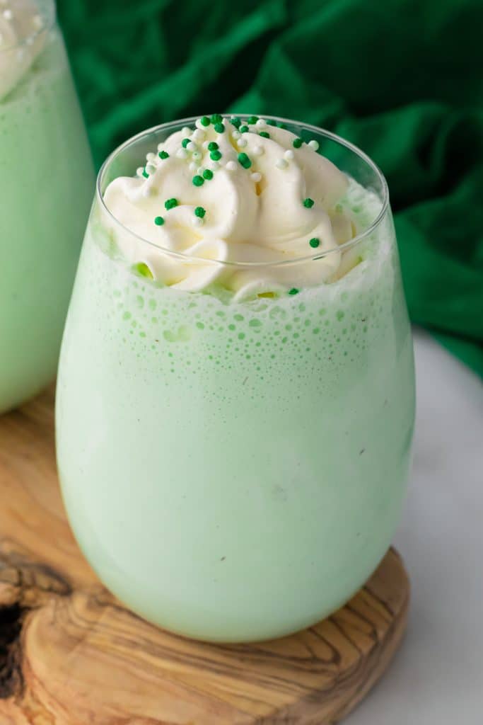 copycat shamrock shake in a glass cup topped with whipped cream and green sprinkles