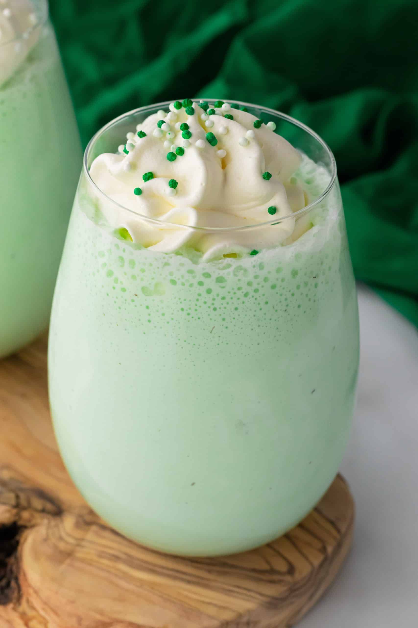 copycat shamrock shake in a glass cup topped with whipped cream and green sprinkles
