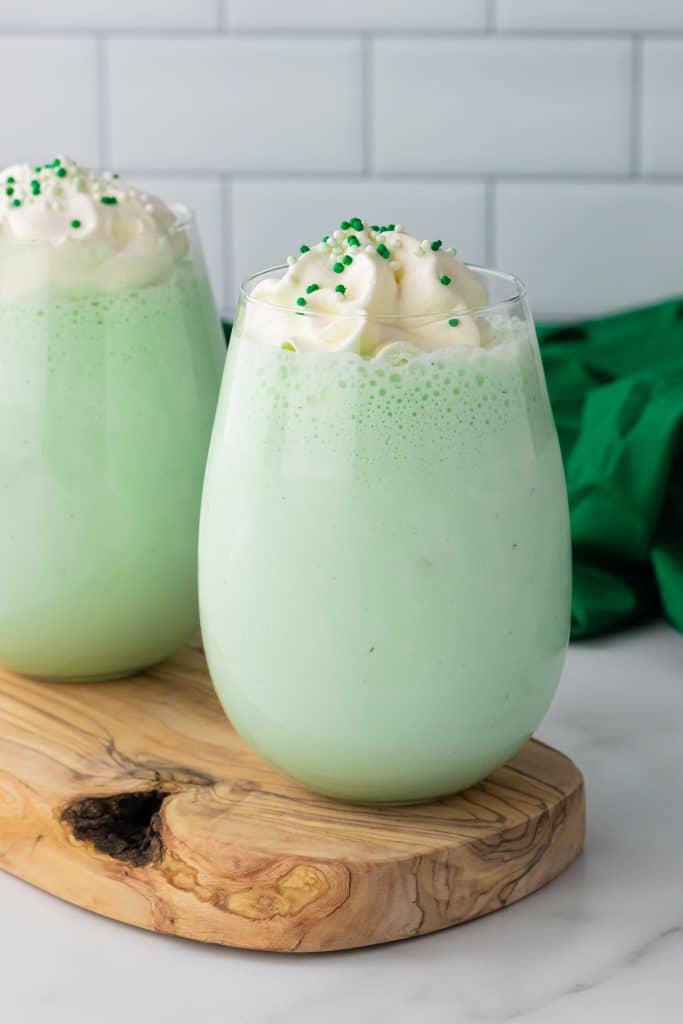 copycat shamrock shake in a glass cup topped with whipped cream and green sprinkles