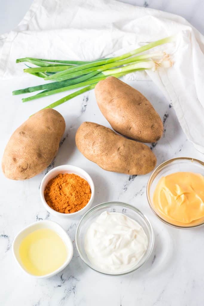 overhead image showing the measured ingredients needed to make taco bell's cheesy fiesta potatoes in the air fryer