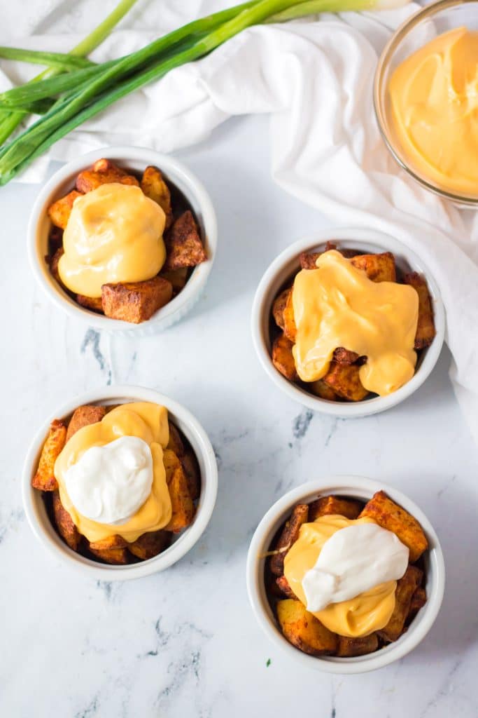 cheesy fiesta potatoes served in four white ramekins