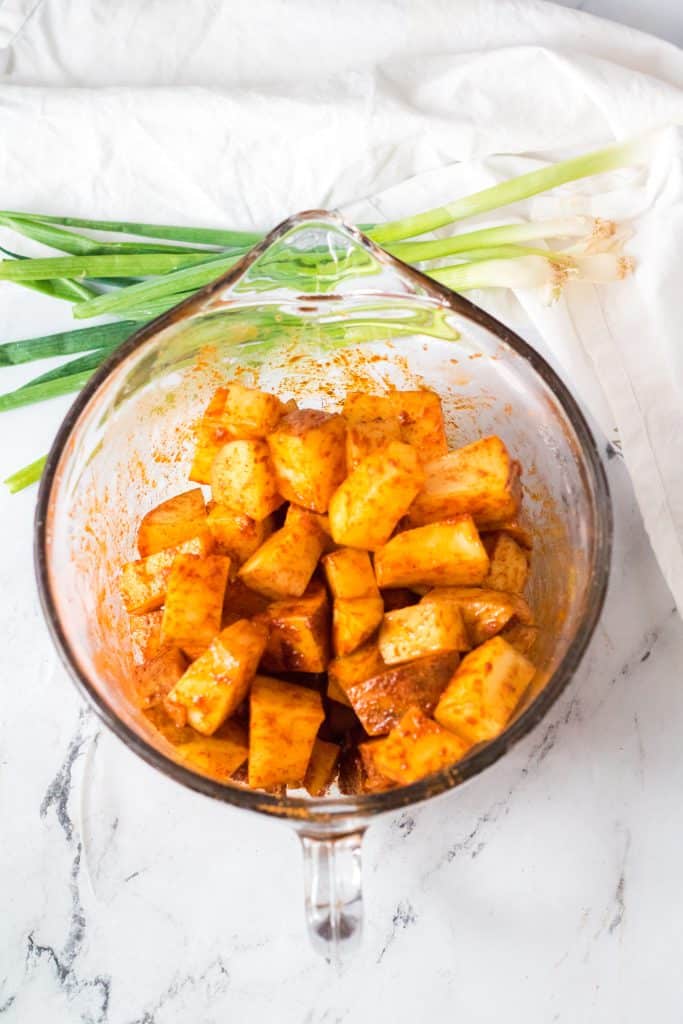 seasoned diced potatoes in a large measuring glass bowl