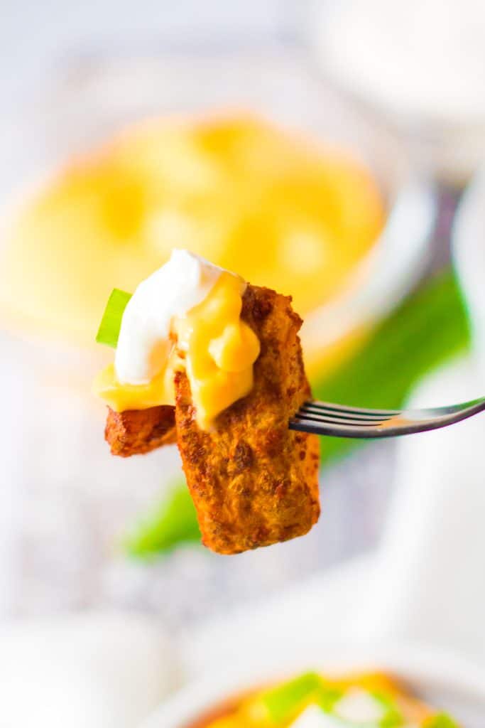 a silver fork holding up a bite of cheesy fiesta potatoes
