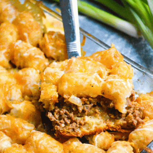 a slice of cheeseburger tater tot casserole with crescent rolls on a silver spatula