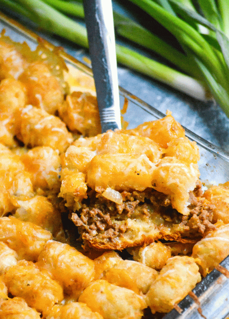 a slice of cheeseburger tater tot casserole with crescent rolls on a silver spatula