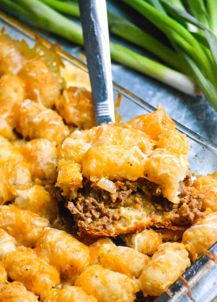 a slice of cheeseburger tater tot casserole with crescent rolls on a silver spatula
