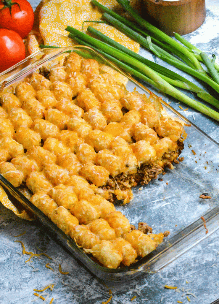 cheeseburger tater tot casserole dish with a large slice removed to show the filling