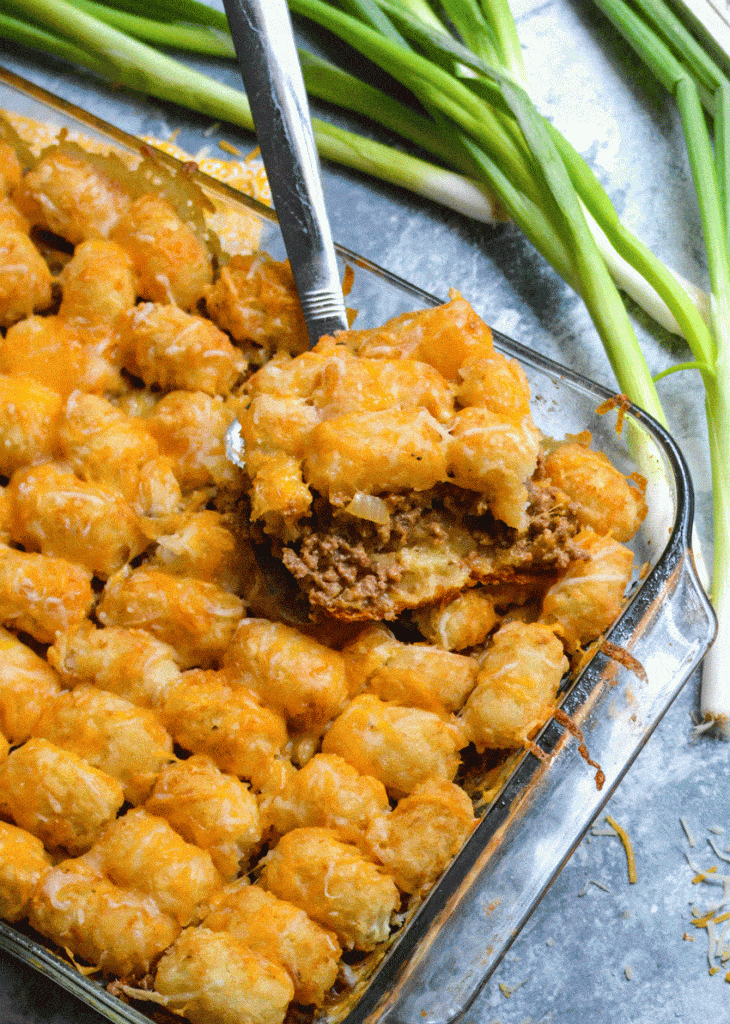 a slice of cheeseburger tater tot casserole with crescent rolls on a silver spatula
