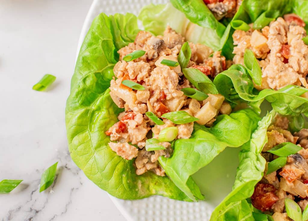 a open faced Asian chicken lettuce wrap topped with sliced green onions