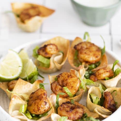 a white plate full of shrimp taco bites in wonton cups