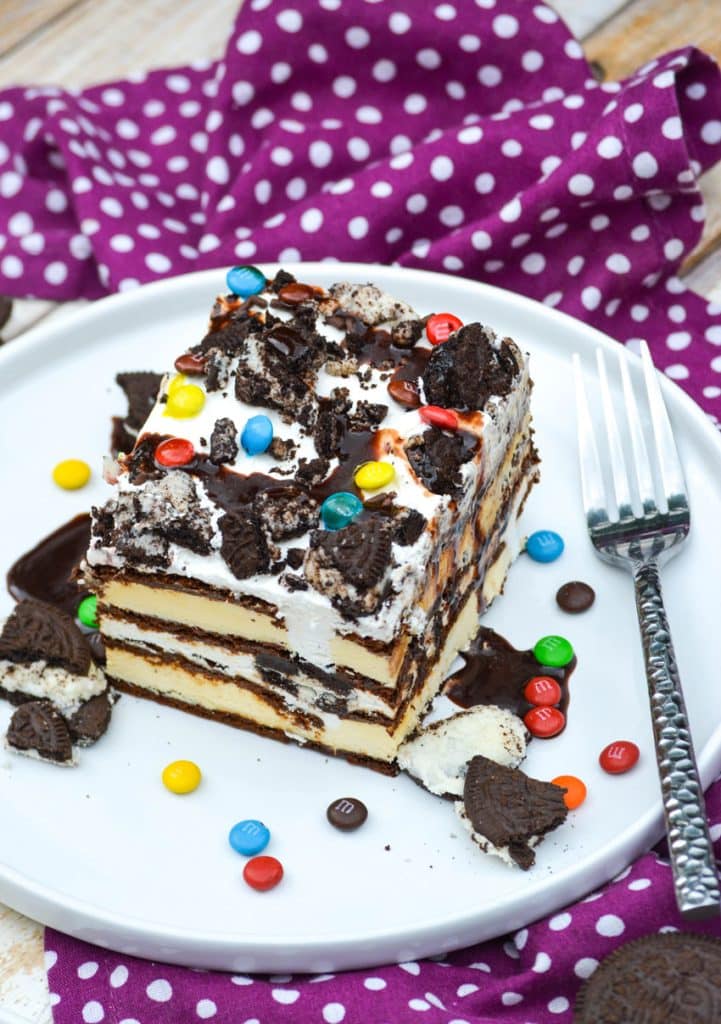 a slice of homemade layered ice cream sandwich cake on a white plate with a silver fork on the side