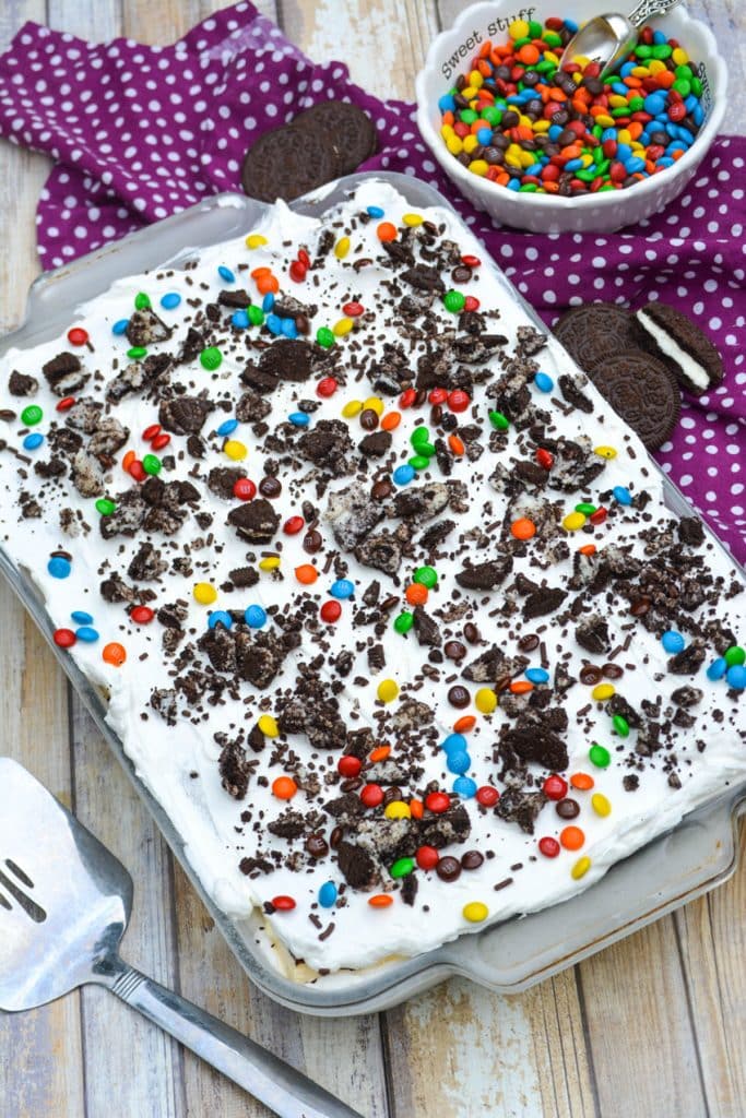 easy ice cream cake in a pyrex baking dish topped with crushed oreos and colorful candy coated chocolate candies