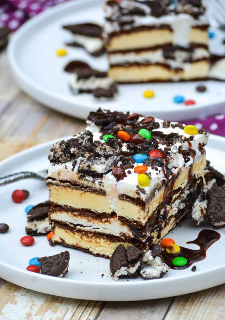 two slices of easy ice cream sandwich cake on a white plates with candies and cookie pieces