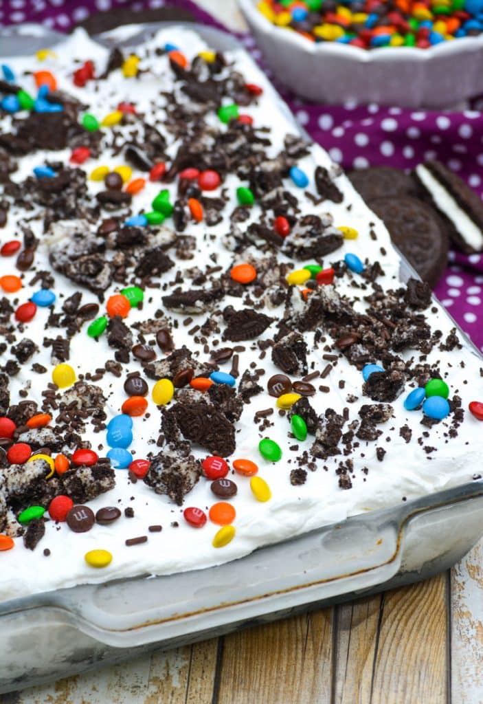 easy ice cream cake in a pyrex baking dish topped with crushed oreos and colorful candy coated chocolate candies