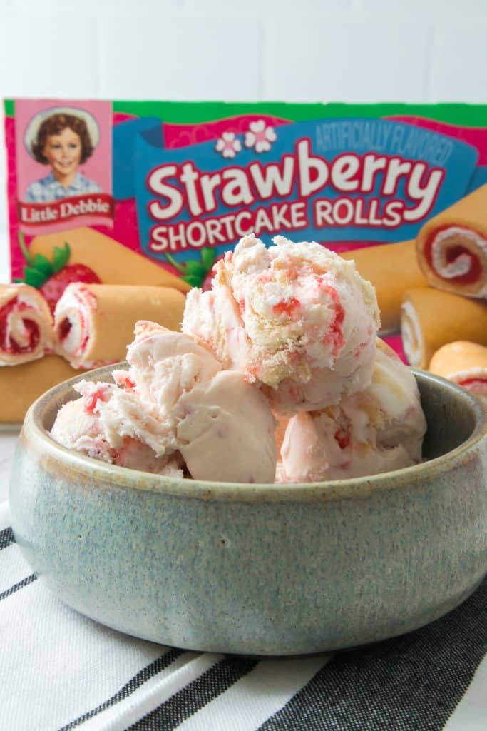 little debbie strawberry shortcake rolls ice cream in a gray bowl in front of a box of shortcake rolls