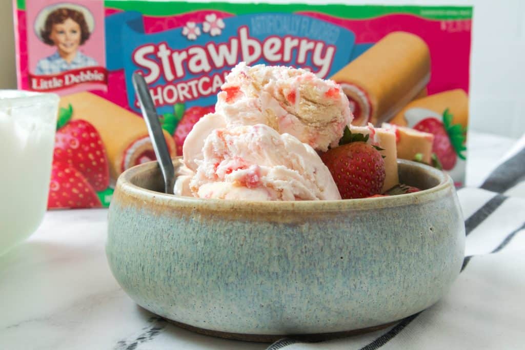 little debbie strawberry shortcake rolls ice cream in a gray bowl in front of a box of shortcake rolls