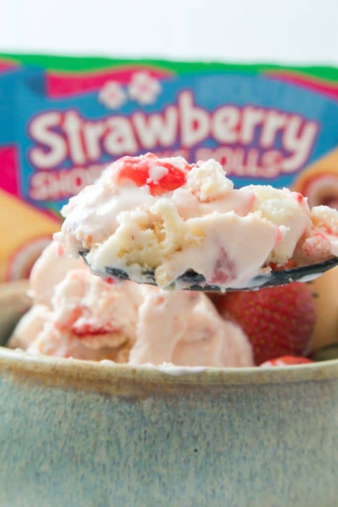 a black spoon holding up a bite of copycat little debbie strawberry shortcake rolls ice cream