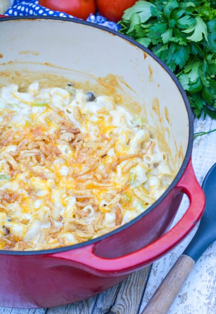 tuna melt macaroni and cheese in a red dutch oven topped with shredded cheese and crispy fried onion pieces