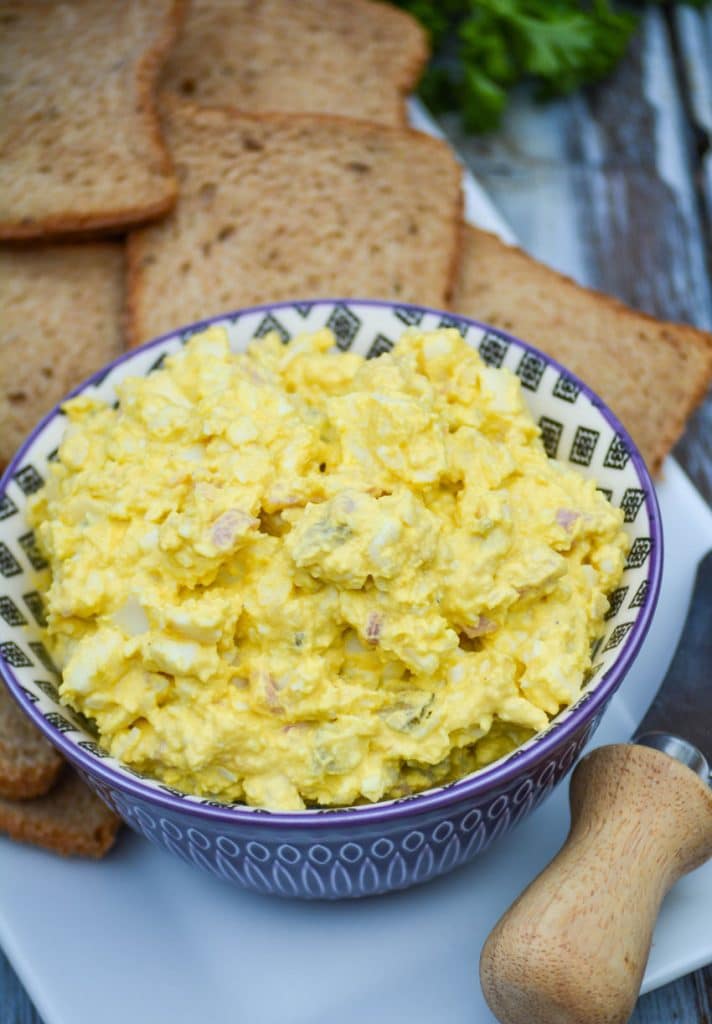 ham and egg salad in a purple bowl surrounded by pieces of party toast