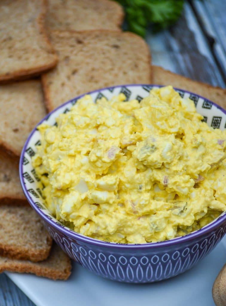 ham and egg salad in a purple bowl surrounded by pieces of party toast